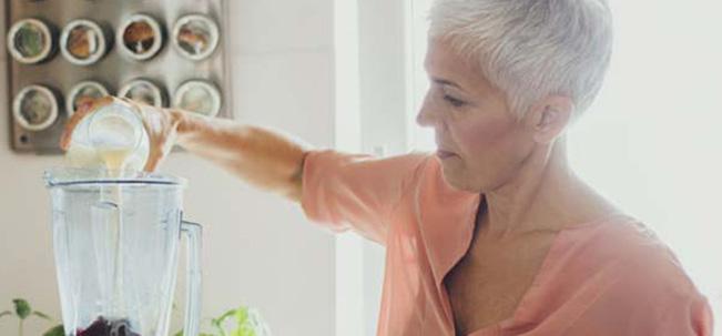 mujer de la tercera edad prepara un batido de Nutren en una licuadora para obtener nutrientes