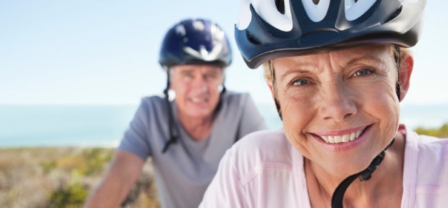 Mujer y hombre mayores de 50 sonriendo por los beneficios de montar bicicleta